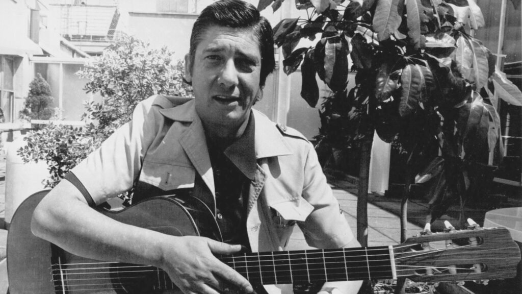 El cantautor y poeta uruguayo, Alfredo Zitarrosa, sosteniendo una guitarra.